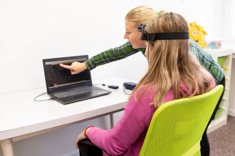 Junge Teenagermädchen und Kindertherapeut während der EEG Neurofeedback-Sitzung. Konzept der Elektroenzephalographie.